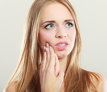 woman in tooth pain touching right cheek